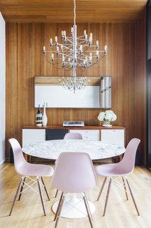 In the dining room, a marble-topped Saarinen table is surrounded with pink Eames chairs. A beautiful credenza by Little Monster Design stylishly sits against the back wooden wall.