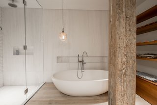 The walls in the shower and behind the tub are clad in slabs of Bianco Dolomiti marble. The floors are the same reclaimed bleached white oak used throughout the house. The light over the tub is the owner's, sourced from souks in Marrakech.
