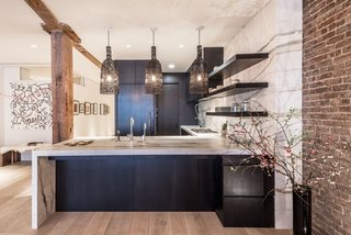 By removing the raised platform that originally had no use, the team was able to double the size of the kitchen and add in a new bathroom on the main floor. The pendants over the peninsula were sourced by the homeowner from AY Lighting, and now echo the dark tones of the white oak cabinetry, which sport walnut interiors.