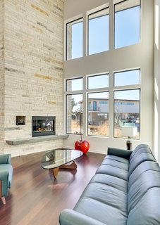 The double-height living room features a dramatic fireplace column, wood floors, and generous windows.