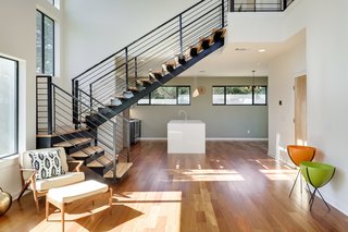 A floating metal staircase is the focal point in the Orion's open living area. A quartz waterfall island in the kitchen is accented with a Heath tile backsplash and Hip Haven lighting.