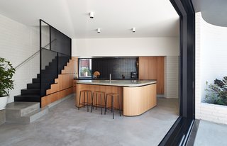 In the new kitchen, oak timber veneer joinery unites concrete floors and counters.