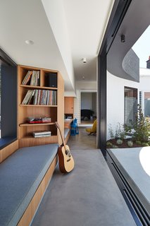 The connecting corridor, or circulation spine, uses built-ins to create space for various activities, such as a family study, a music spot, and reading nooks.