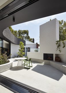 In this view, one can see how the curved addition makes space for an outdoor seating area with a fire pit, and eventually meets the clapboard form of the original house.