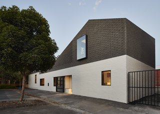 "Stitching the existing white weatherboard cottage into its more robust industrial surrounds, the new addition uses brick work painted white at the first level to connect to the white weatherboard and then black at the top level to engage with the local industrial precinct," say the architects.
