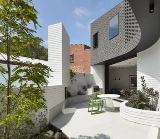 On the western side of the home, the brick addition becomes sinuous to carve out leisure spaces in a new private courtyard, which is entirely enclosed by a white brick boundary wall. Large openings to the interior ensure seamless indoor/outdoor flow for the homeowners.