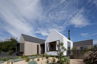 From this angle, all three buildings can be seen, two of which are clad in wood. The foremost building is wrapped in white polycarbonate.