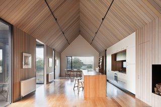 High ceilings make the narrow footprint feel more expansive. A short, glazed passage connects the polycarbonate structure to this room. That passageway also hosts the front entry.