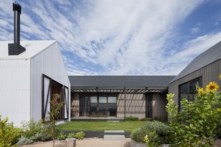 The three structures are linked by a covered walkway and surround a north-facing courtyard protected from coastal winds. There is no fence to encourage interaction with neighbors.