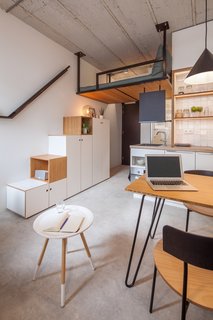 The bed is attached to the ceiling and hangs on a platform two meters above the floor. Elevating the bed allows the main living areas and storage to be tucked below.