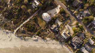 A low-lying vegetative barrier separates the home from the beach.