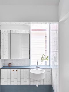At the sink area is built-in storage and a floating glass medicine cabinet.