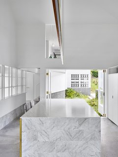 A courtyard on the other side of the kitchen makes the room feel as though it is surrounded by the outdoors. Double-height ceilings allow for a cut-out into the upper level, connecting upstairs and down.
