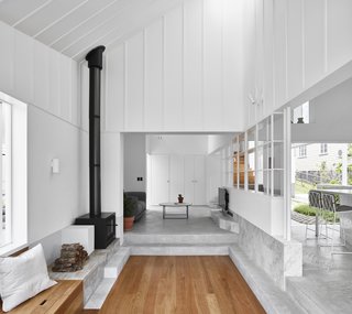 The garden room has a built-in bench and free-standing fireplace. This area works as overflow for the adjacent kitchen, which allows people to see the cook in action, yet still lounge. The living room is a bit more removed, located just two concrete steps away.