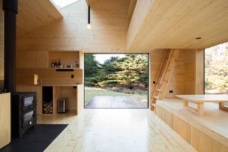 The open-plan interior has been sheathed in light-colored wood to create a sense of enclosure, as well as an escape from the modern world. The low-lying exterior decks have been designed to not require railings, ensuring the sightline to the surrounding wilderness goes unimpeded.