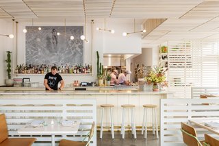 Above the bar, a large photo of Keith Richards floating in a swimming pool is juxtaposed against the pale colors and caramel leather scheme, conjuring a fun, rock-and-roll vibe.