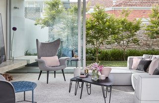 In this view of the living room, the landscaped courtyard is visible. "External spaces become an extension of living zones, maximizing the usable area of the site and contributing to the sense of generosity of space," the architects explain.
