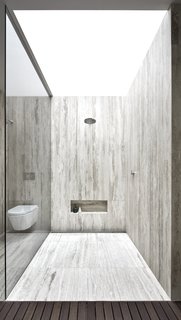 The shower is enclosed in travertine and topped with a skylight.