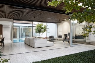 The glass addition wraps a tiled courtyard with a slim lap pool. The addition is bordered on the other side with another landscaped courtyard.