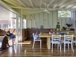 The pavilion relates to the original house in the exterior framework, as both use white-painted timber. Glass doors retract for full outdoor access.