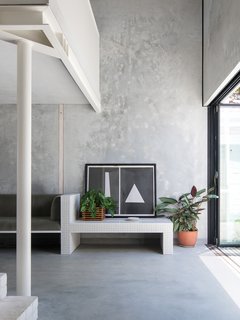 In the main living area, large doors open to the backyard, while a built-in sofa and bench clad in tile are tucked under the mezzanine level, which hosts the bedroom and en-suite bathroom. Internal spaces are intended to flow easily into each other to maximize the floor plan.