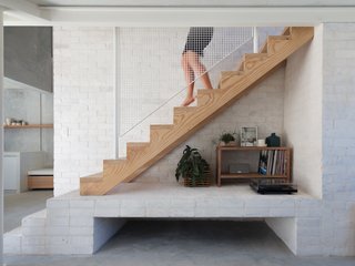 Recycled bricks form a core wall and support the central staircase. A white metal railing is another layer of texture in the scheme. "The project relied heavily on craft, detailing, and a raw material or 'wabi-sabi' spec to provide amenity and delight in the small footprint," say the architects.