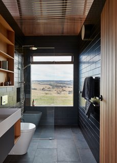 The view is the focal point in a bathroom sheathed in charcoal tile and complemented by wood accents.