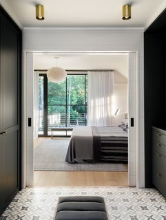 The view into the bedroom shows closet. Cabinetry has been integrated on both sides, and the walls have been painted with Benjamin Moore Flint.