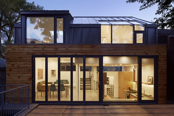 In order to maximize space, the architects utilized a split-level design that includes the living areas on the main level, two upstairs bedrooms, and a walk-out basement beneath the dining room. The wood siding was salvaged and restored from the previous building on-site, in order to bring warmth to the gray, seamed metal and reference the neighborhood's past.