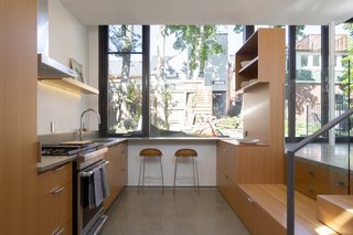 Sinking the kitchen floor let the architects optimize the glazing. The breakfast bar at the end of the room lets diners look out over the backyard, while the nearby freestanding cabinetry, designed by Built Work Design, offers streamlined storage that doesn't detract from the sight lines.