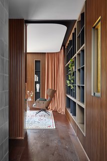A curved ceiling gently hovers over the stricter lines of the wall paneling and inset shelves.
