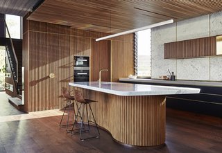 The shape of the kitchen island "reflects the local iconic beachside concrete kiosk building saved by the community," said the architects.
