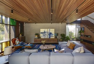 In the living room, the wood and concrete shell is accented with a steel stair railing and a window wall with a Mondrian pattern in the glazing.