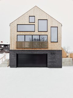 The natural slope of the site was perfect for dividing the house into split levels. The exterior is clad in heat-treated pine that has aged to a soft gray, which contrasts nicely with the charcoal bricks.