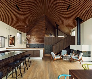 "They wanted a very practical house, with separate zones for kids and adults," said Taugbøl. "Because of the split levels, the experience of the space varies when you walk through it," and ascend the staircase. "The acoustics are also great due to the wood paneling in the ceiling." The Raimond pendent lights are from moooi, and the fireplace seating is IKEA.
