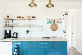 A small kitchenette allows guests to brew a cup of coffee or tea, or prepare a light meal. The brilliant blue, high-gloss cabinets are IKEA, similar to the KALLARP line, adorned with Schoolhouse Electric's Edgecliff Pulls. An oak wood countertop completes the picture.