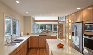 The renovated kitchen features quartz counters and natural maple cabinets, and it flows easily with the rest of the renovated open plan.