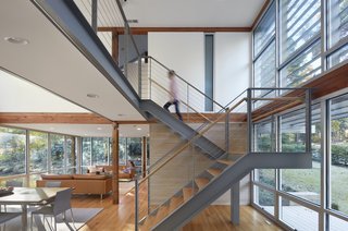 A new steel staircase with wood tread and a cable railing does not block views outside. The double-height window systems used at the front and back of the home are glass storefront units from YKK.