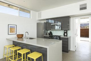 This Modern Homestead With a Vintage Trailer Offers Adventure in California's High Desert - Photo 4 of 10 - Bright, yellow stools accent a sleek kitchen in the main home.
