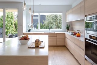 An alternate view of the kitchen shows custom millwork and a continuous wood backsplash, creating an effortlessly seamless connection.