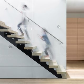 The stair, a sculptural piece composed of glass guards and open wood risers, allows light to fall further into the interior.