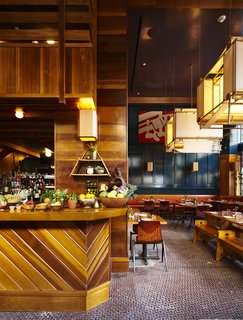 A 1920s Office Building Is Revamped as a Craftsman-Inspired Hotel in Los Angeles - Photo 5 of 10 - Rich teals, gold accents, warm wood tones, and accent greenery create a warm and textured dining atmosphere.