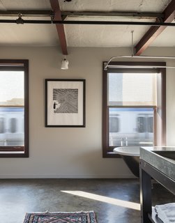 History and Modernity Meet in This Industrial Hotel and Restaurant in Philadelphia - Photo 7 of 11 - An original clawfoot tub rests below the windows, looking out to the train tracks beyond. A poured concrete sink with steel legs introduces modern elements that blend with the historic character.