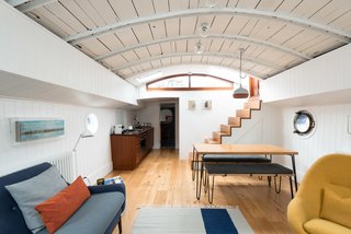 An uplifting color palette and restored midcentury furnishings, such as the 60s Greaves and Thomas Egg chair, fill the living space. 
