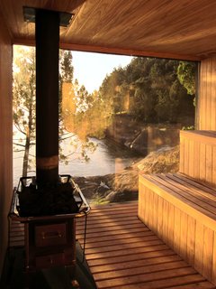 Encased with wood and glass, and surrounded by trees and rocks, the sauna is a meditative hideaway with private lakefront views. 