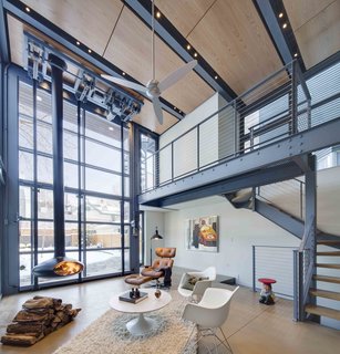 The interior living space is warmed by the wood panels above and a hanging fireplace.