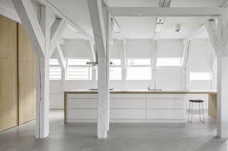 The fully-integrated kitchen is obscured by oak cabinetry, corresponding with a large island with an integrated cooktop and sink. 