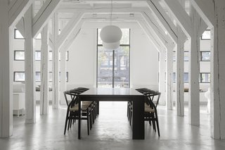 Hans J. Wegner Wishbone Chairs surround the large dining table on axis with the grand, exterior windows. 