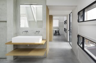 A custom solid surface basin on oak wooden shelves, in combination with a Zuchetti faucet and a Vibia Linestra light fixture, make for a warm, contemporary bath vanity.