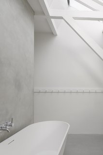 A white, freestanding solid surface tub by Riho Barcelona and a Zuchetti faucet outfit an additional bath, blending nicely into the minimal palette.